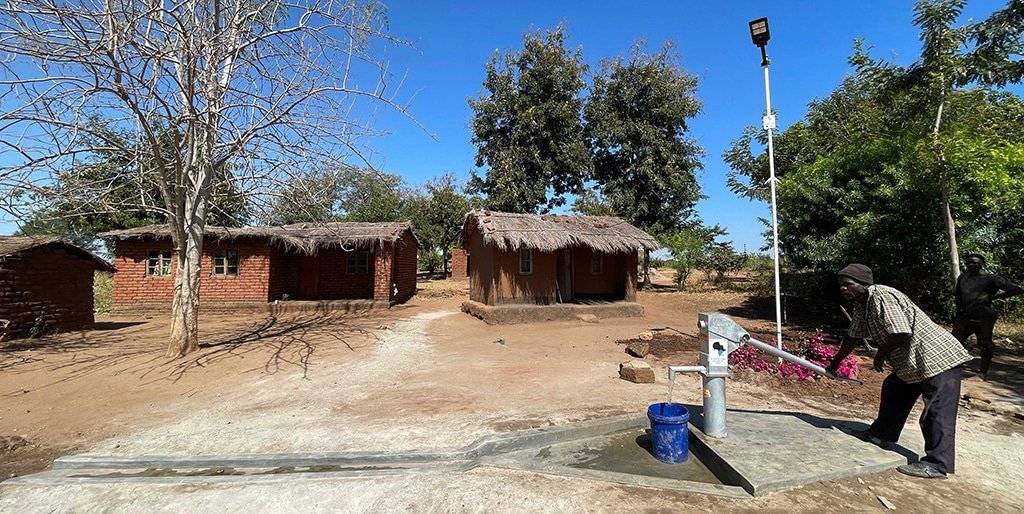 Pompa d'acqua e lampione solare davanti alle case di un villaggio malawiano