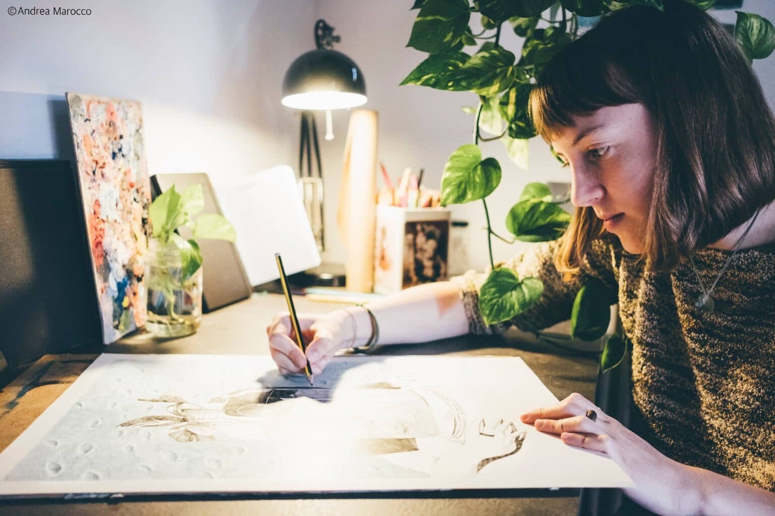Donna che disegna alla scrivania circondata da piante