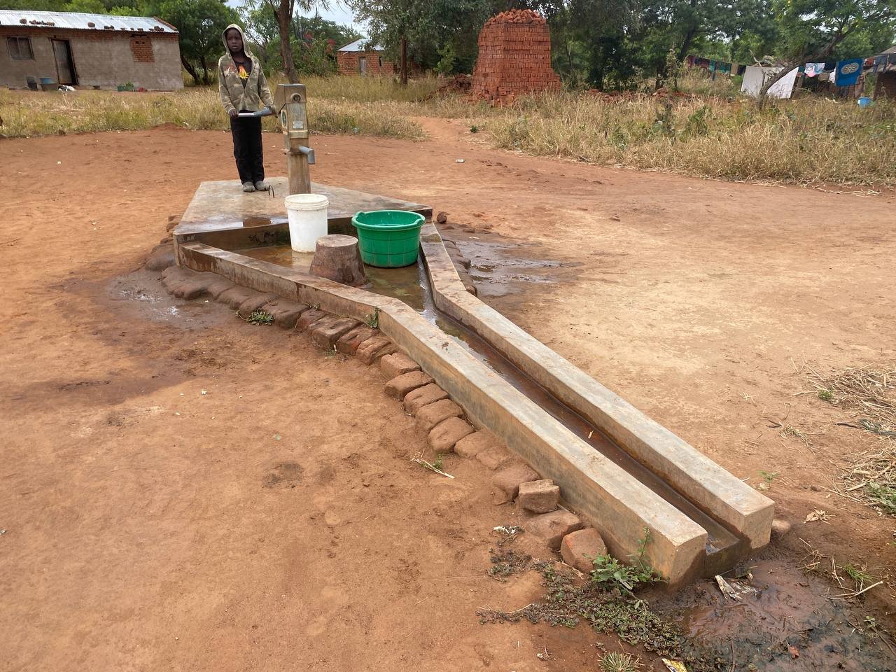 Donna che raccoglie acqua dalla nuova pompa in Malawi