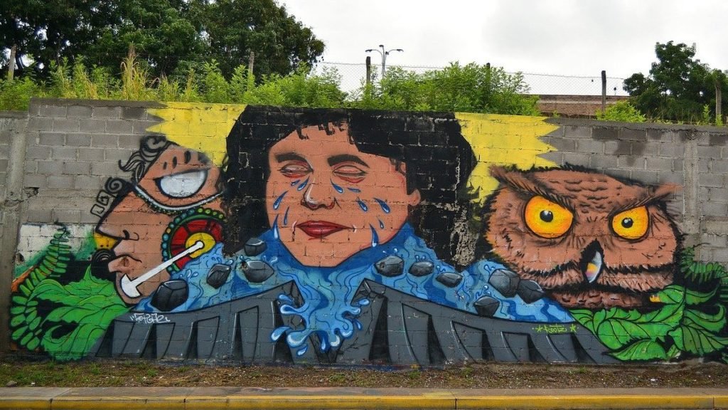 Murale con volti e una civetta su un muro di periferia