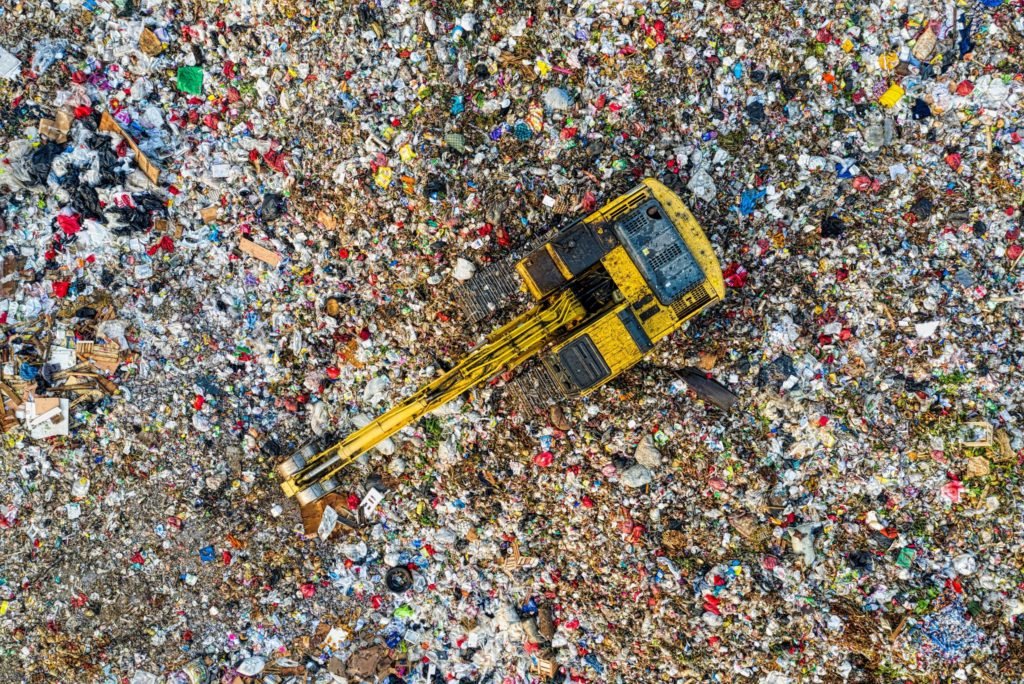 Escavatore al lavoro su una discarica vista dall'alto